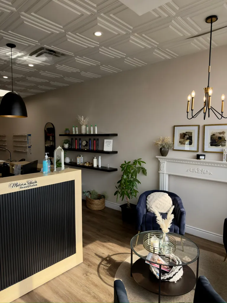 The reception desk and waiting area at Modern Touch Beauty Salon, with a coffered ceiling, black slat counter, and navy velvet seating